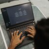 Close-up of hands typing on a laptop displaying ChatGPT interface indoors.